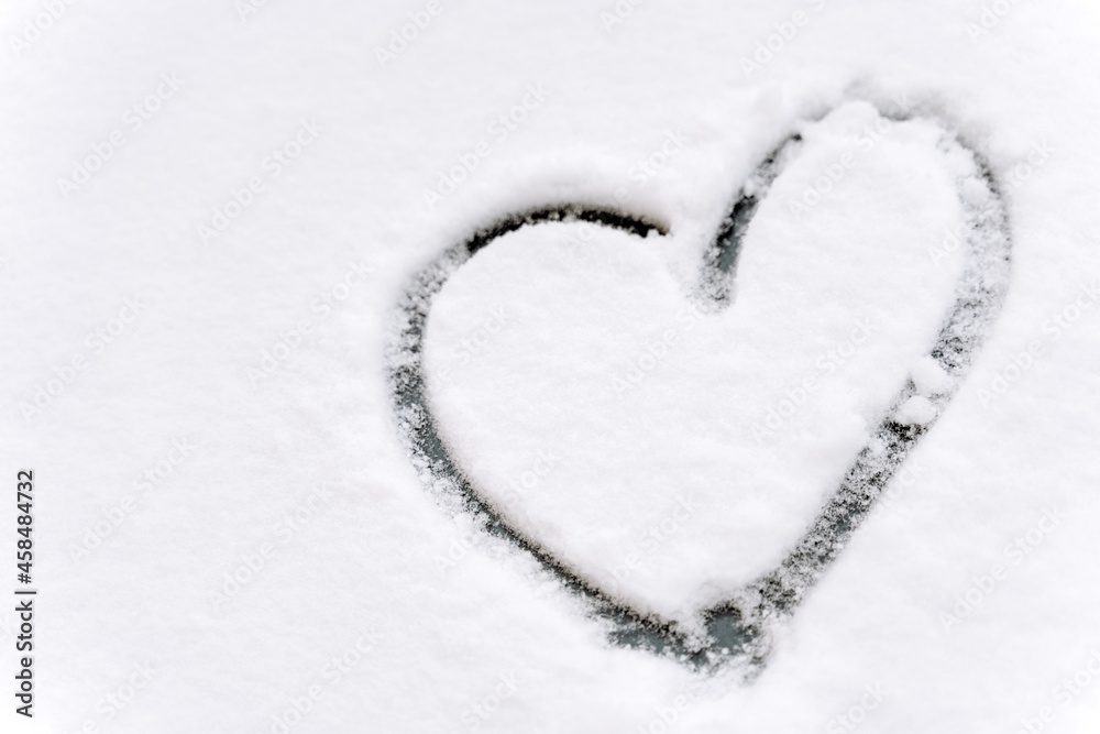 Close up view of the heart shape drawn on a car windshield covered with fresh white snow. Winter concept. Stock photo