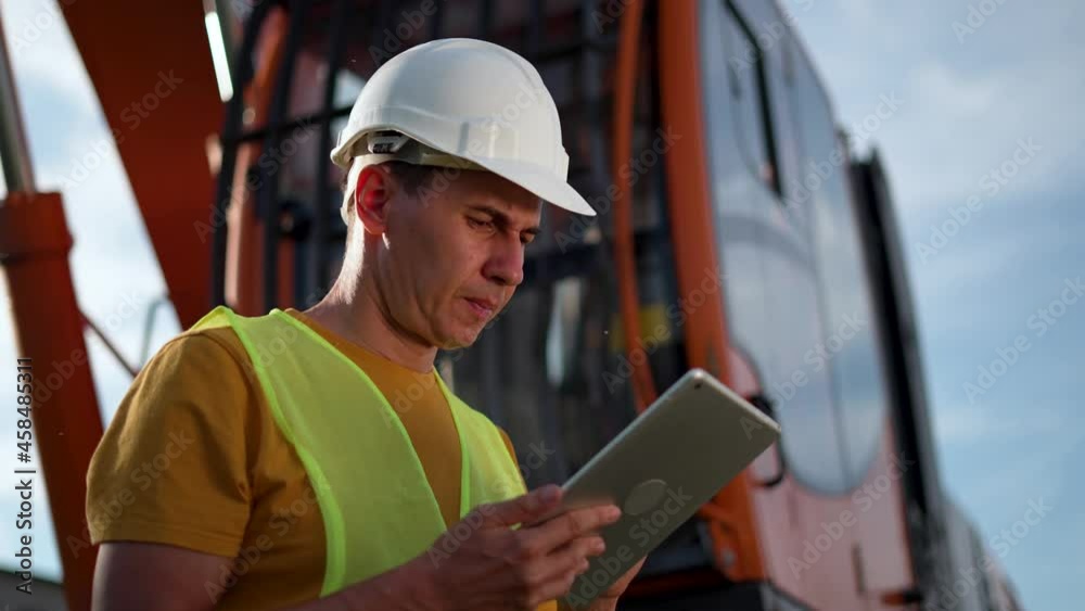 Senior engineer with tablet and in helmet. Building business. Senior engineer production planning. Construction, production of building material. White helmet on head of the engineer. Business concept Senior engineer with tablet and in helmet. Building business. Senior engineer production planning. Construction, production of building material. White helmet on head of the engineer. Business concept