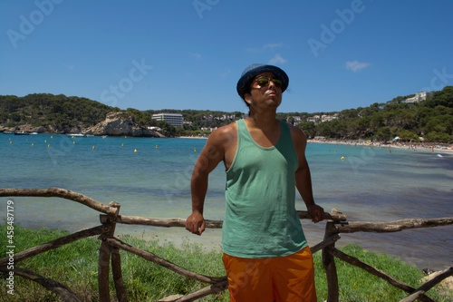 young brown-skinned boy on vacation in Menorca looking to the right with the background of the sea and the beach, photo located in Balearic Islands, Spain © DarwinDSBNewYorkcity