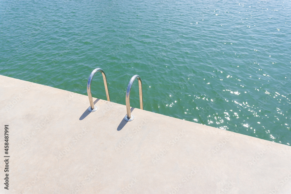 Swimming pool ladder on a concrete pier of a maritime port in the Mediterranean Sea Swimming pool ladder on a concrete pier of a maritime port in the Mediterranean Sea