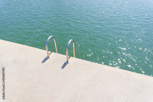 Swimming pool ladder on a concrete pier of a maritime port in the Mediterranean Sea photo
