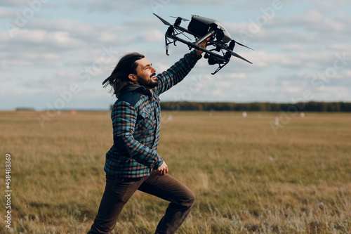 Man pilot holding quadcopter drone in handand running at outdoor field photo