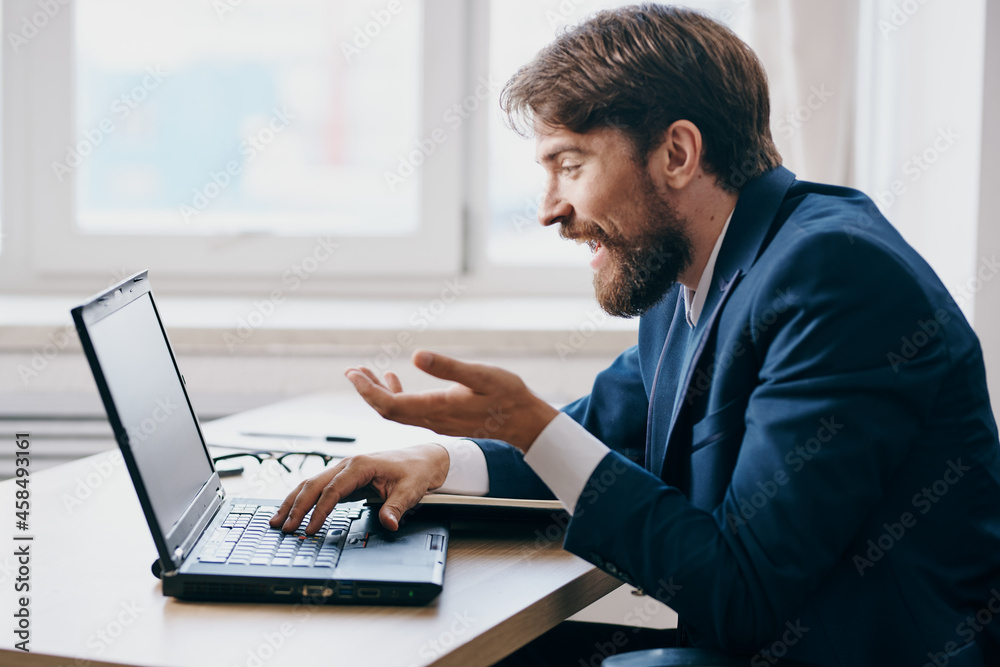 manager in the office at the desk in front of a laptop career official manager in the office at the desk in front of a laptop career official