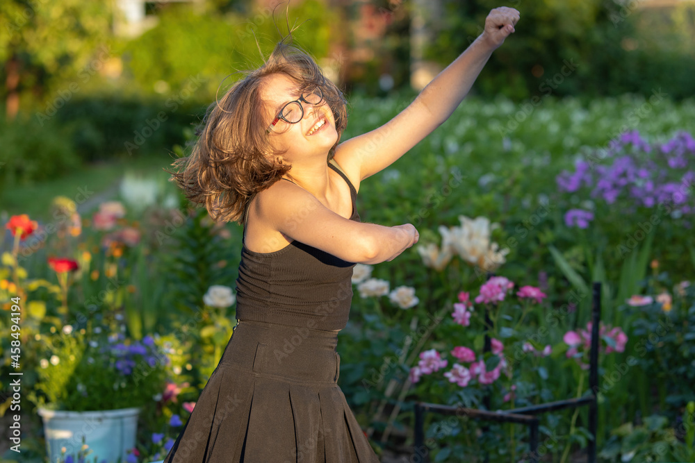Girl in glasses with long hair dancing in a blooming summer garden Girl in glasses with long hair dancing in a blooming summer garden