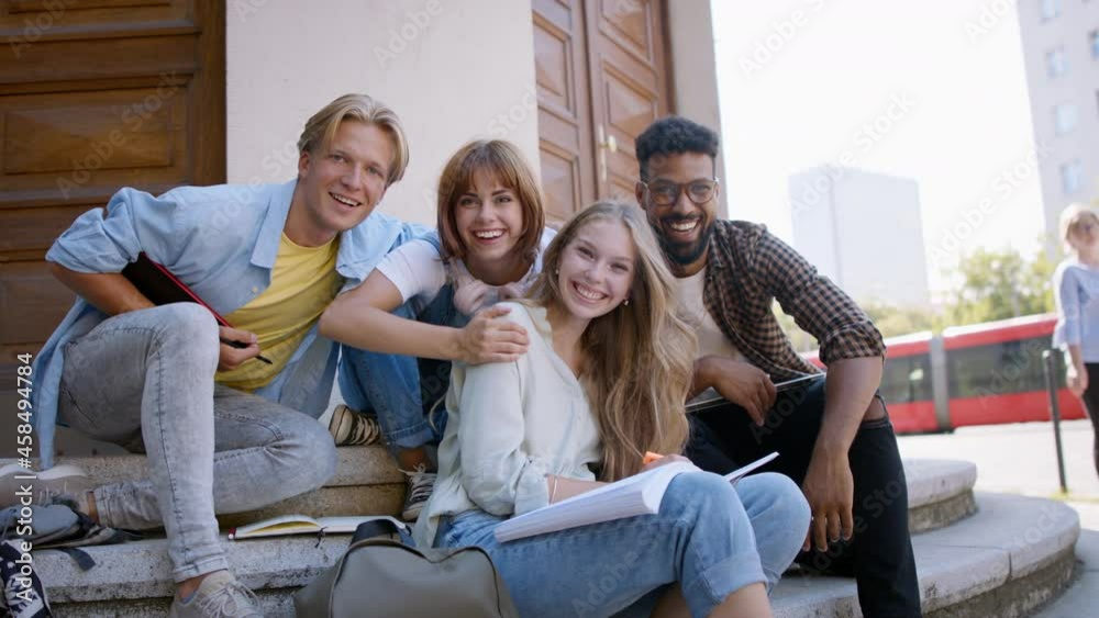Group of students sitting on staircase, working school project and looking at camera. Group of students sitting on staircase, working school project and looking at camera.