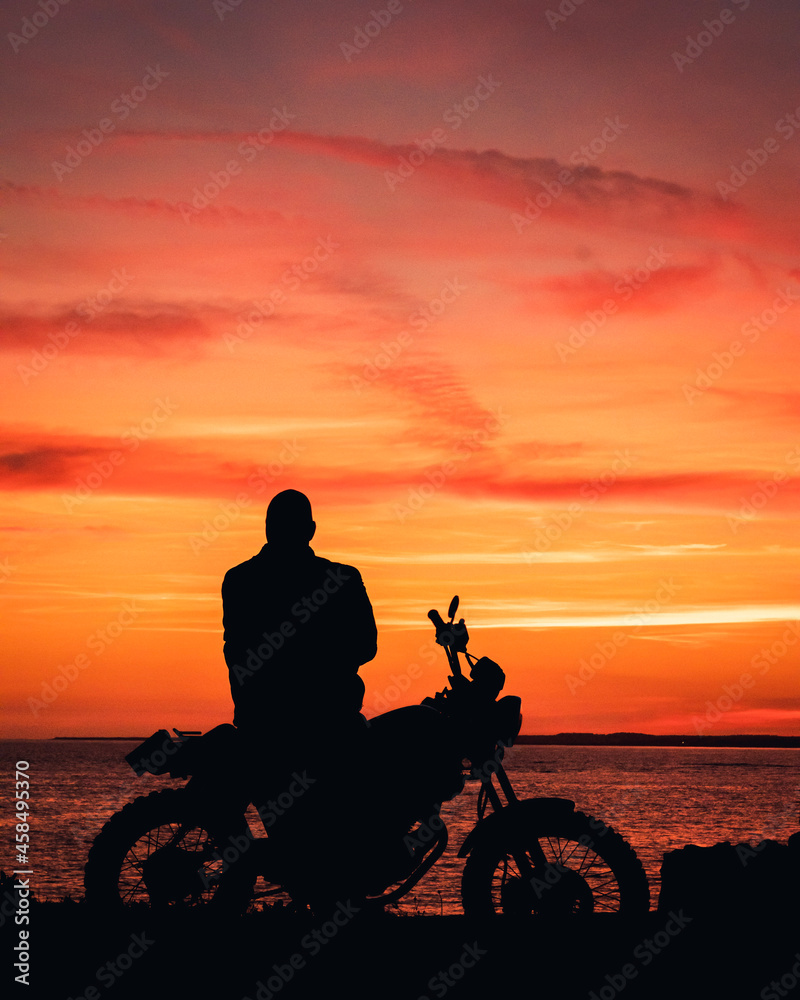 Fototapeta premium silhouette of a biker on a motorcycle, orange and pink sunset with text space copy space