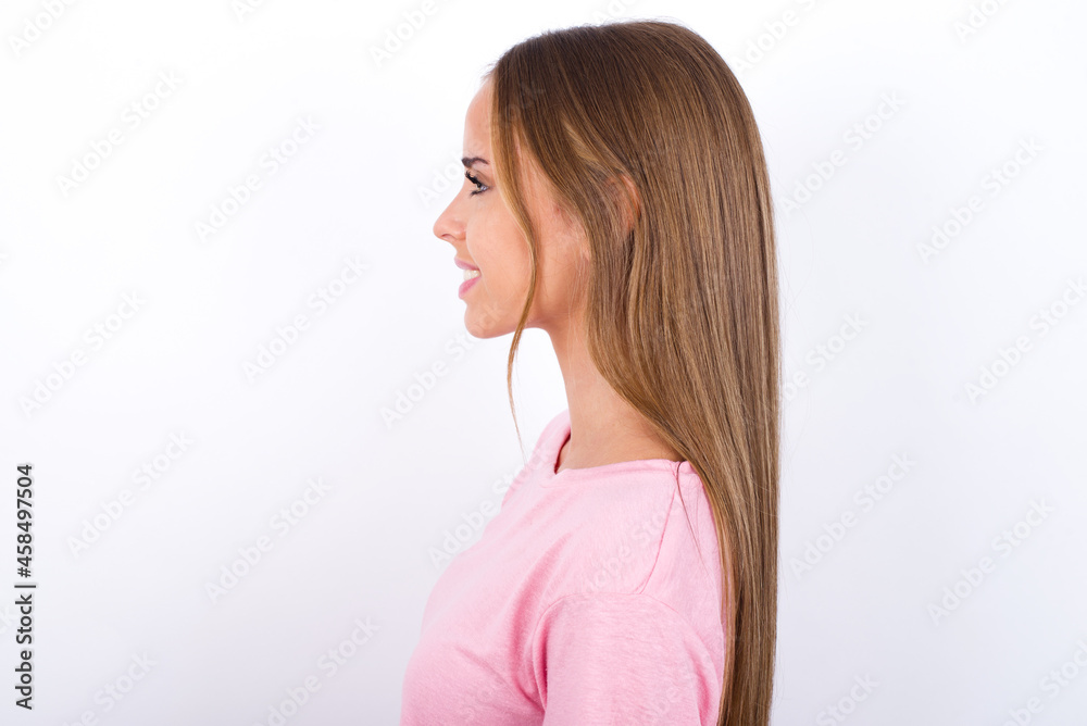 Profile of smiling beautiful blonde girl wearing pink t-shirt on white background with healthy skin, has contemplative expression, ready to have outdoor walk. Profile of smiling beautiful blonde girl wearing pink t-shirt on white background with healthy skin, has contemplative expression, ready to have outdoor walk.