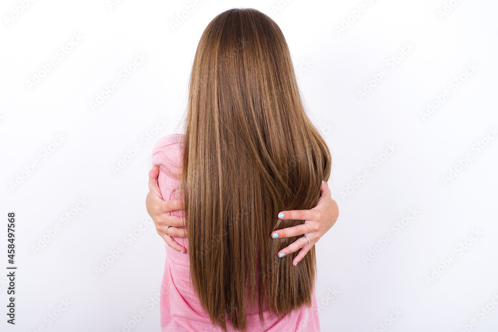 beautiful blonde girl wearing pink t-shirt on white background hugging oneself happy and positive from backwards. Self love and self care. beautiful blonde girl wearing pink t-shirt on white background hugging oneself happy and positive from backwards. Self love and self care.