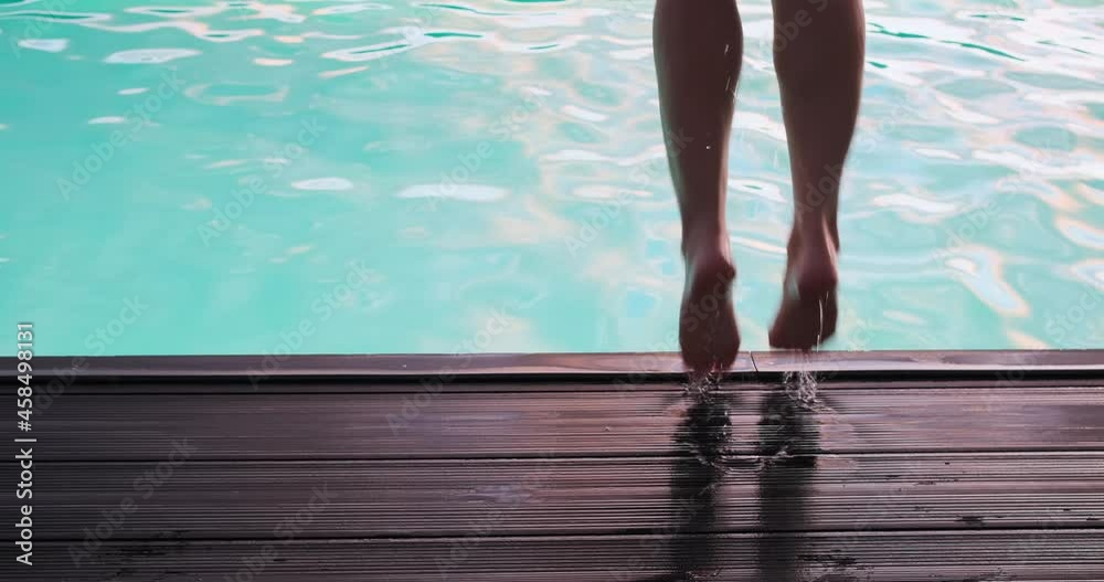 Low section of woman in swimsuit jumping into swimming pool