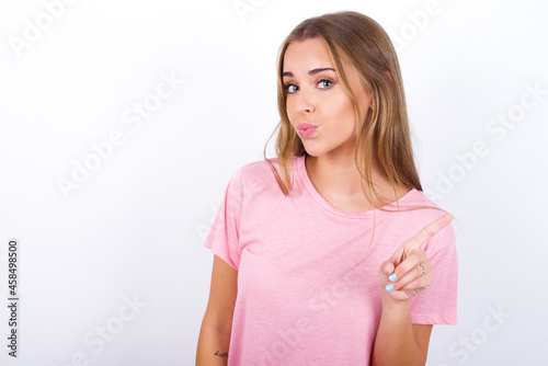 No sign gesture. Closeup portrait unhappy beautiful blonde girl wearing pink t-shirt on white background raising fore finger up saying no. Negative emotions facial expressions  feelings.