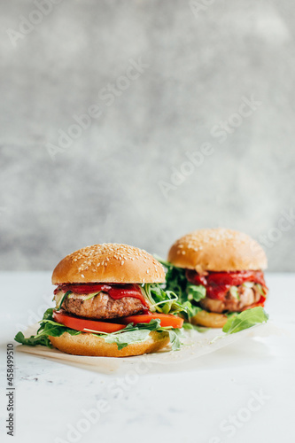 close-up of two burgers on a white table on a gray background
