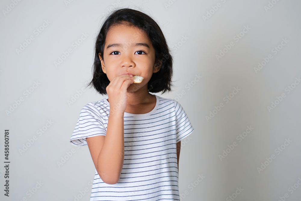 Asian little girl eating biscuit isolated on white background Asian little girl eating biscuit isolated on white background