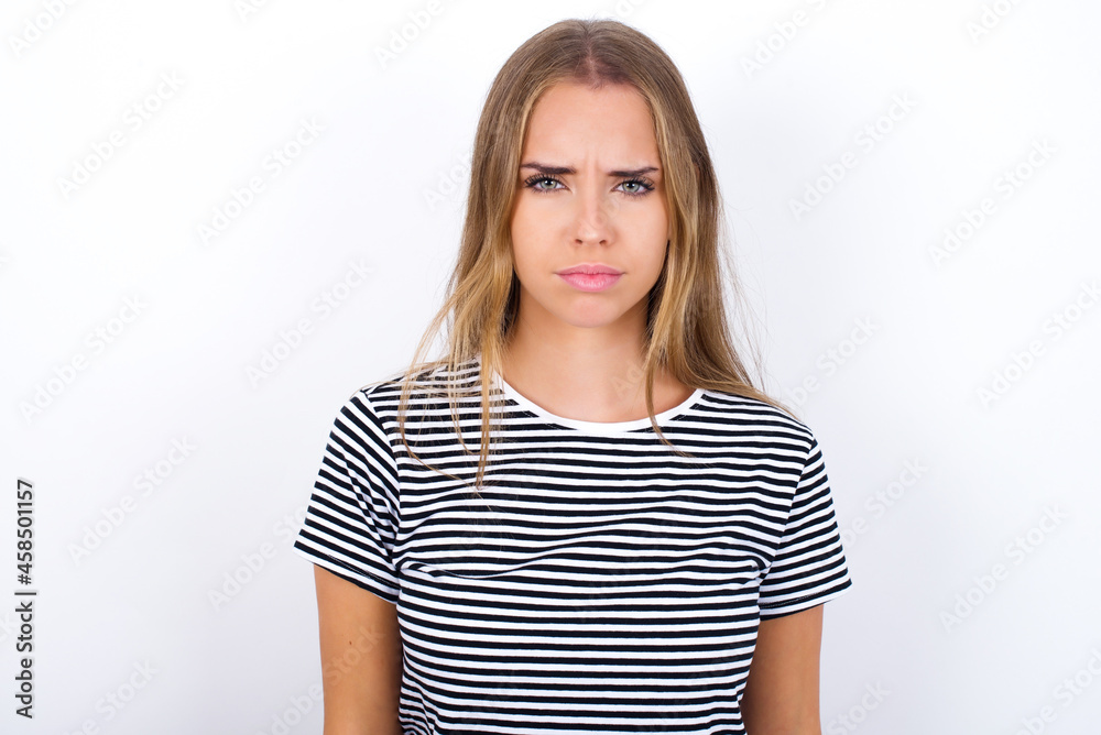 beautiful blonde girl wearing striped t-shirt on white background Pointing down with fingers showing advertisement, surprised face and open mouth beautiful blonde girl wearing striped t-shirt on white background Pointing down with fingers showing advertisement, surprised face and open mouth