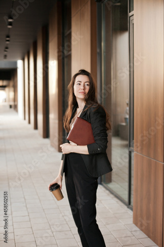 Young millennial businesswoman working near office building holding tablet