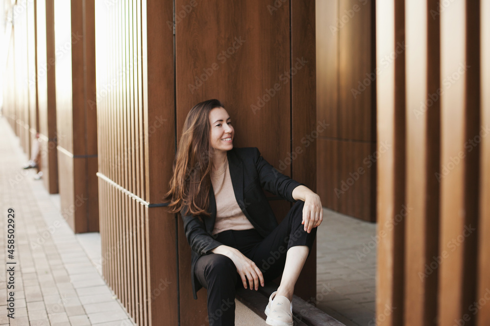 Young millennial businesswoman sitting by the office building