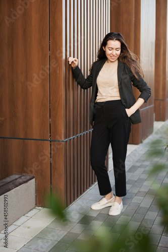 Businesswoman in black pantsuit standing near office building © Dina