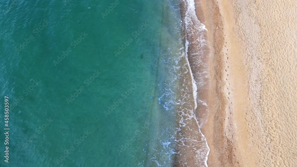 Top view on the waves of turquoise and clear sea water washing the sand on the shore. Summer warm sand and rest by the sea. Top view on the waves of turquoise and clear sea water washing the sand on the shore. Summer warm sand and rest by the sea.