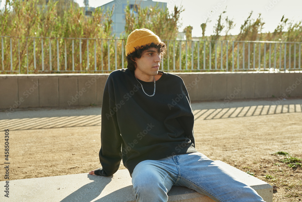 Cute young man sitting on bench outdoors Cute young man sitting on bench outdoors