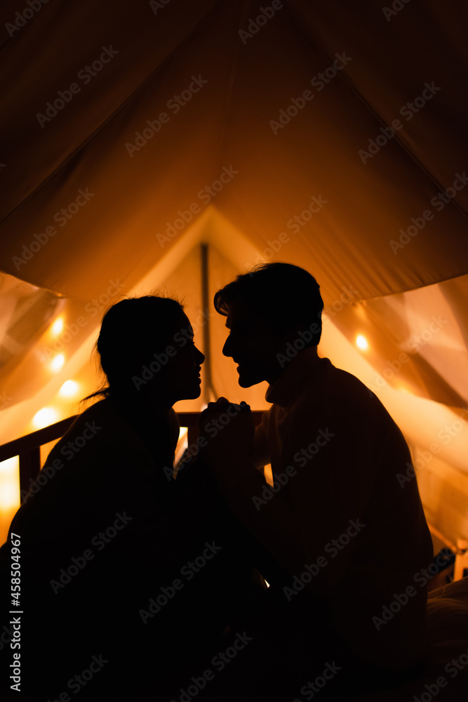 Side view of silhouettes of couple in glamping house in night