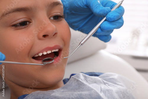 Dentist examining little boy s teeth in modern clinic  closeup