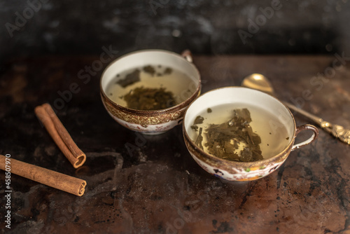 Photography two china cups filled with tea leaves in hot water