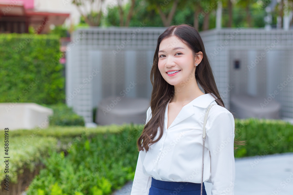 Asian confidence business woman wears a white shirt and smiles happily while she walks out to workplace in the morning. Asian confidence business woman wears a white shirt and smiles happily while she walks out to workplace in the morning.