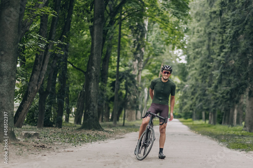 Positive man in activewear taking break after cycling