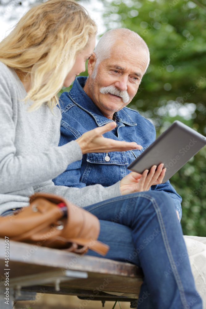 woman showing tablet screen to elderly gentleman woman showing tablet screen to elderly gentleman