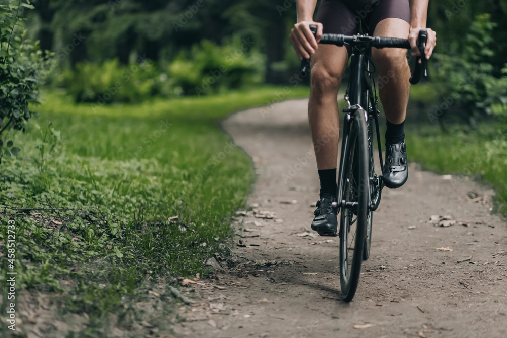 Fototapeta premium Close up of cyclist with strong legs riding at green park