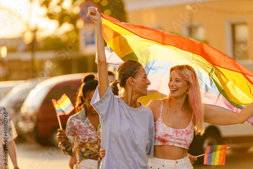 Lesbian couple walking with rainbow flag during pride parade