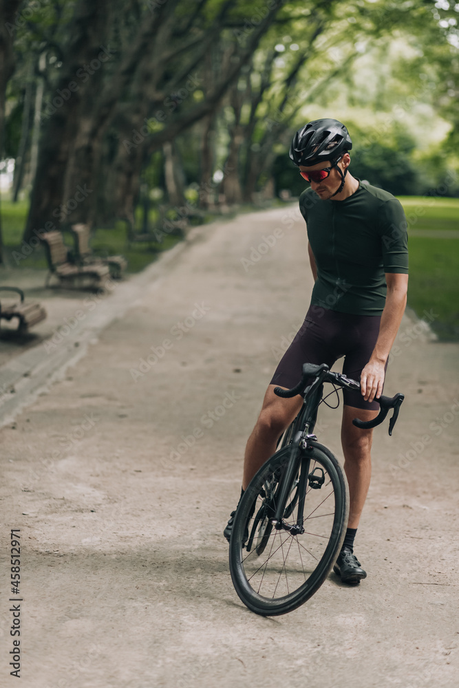 Strong caucasian man in activewear resting on bike outdoors Strong caucasian man in activewear resting on bike outdoors