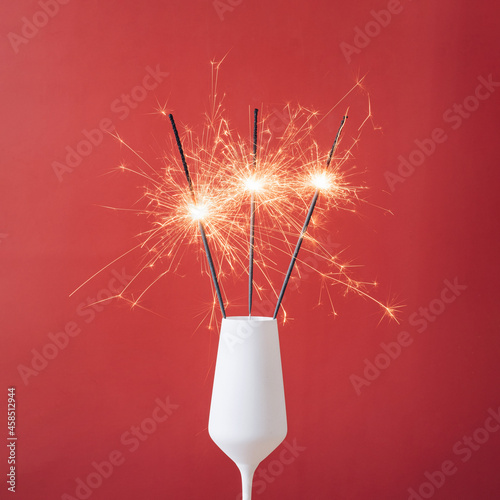 Close-up of three sparklers in a white glass of champagne photo