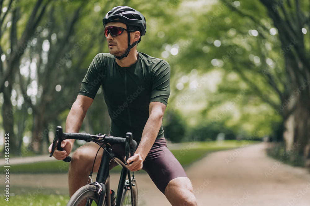 Obraz premium Caucasian cyclist in glasses and helmet relaxing at park