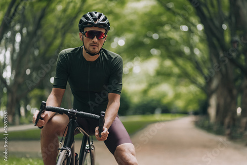Active man in helmet and glasses sitting on bike outdoors