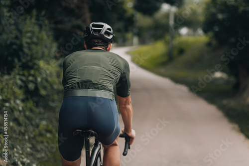 Fototapeta Naklejka Na Ścianę i Meble -  Back view of cyclist in activewear training at park