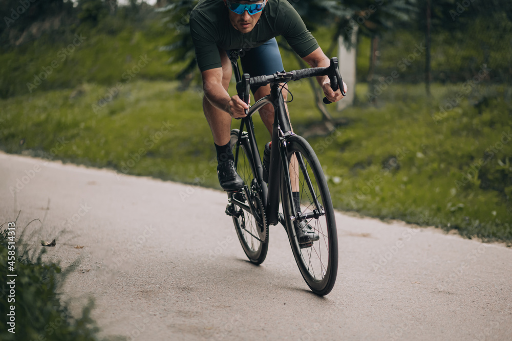 Active male athlete using bike for training on fresh air Active male athlete using bike for training on fresh air