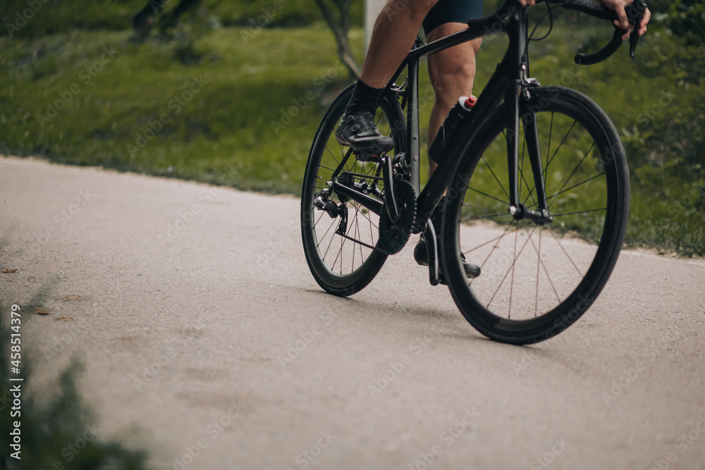 Close up of man muscular legs riding bike at green park Close up of man muscular legs riding bike at green park