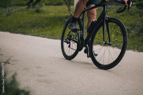 Close up of man muscular legs riding bike at green park © Tymoshchuk