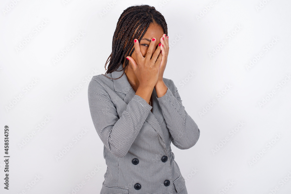 MODEL covering face with hands and peering out with one eye between fingers. Scared from something or someone. MODEL covering face with hands and peering out with one eye between fingers. Scared from something or someone.