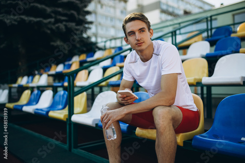 Portrait of young Caucasian man, male athlete, runner isolated at public stadium, sport court or running track outdoors. Summer sport games.