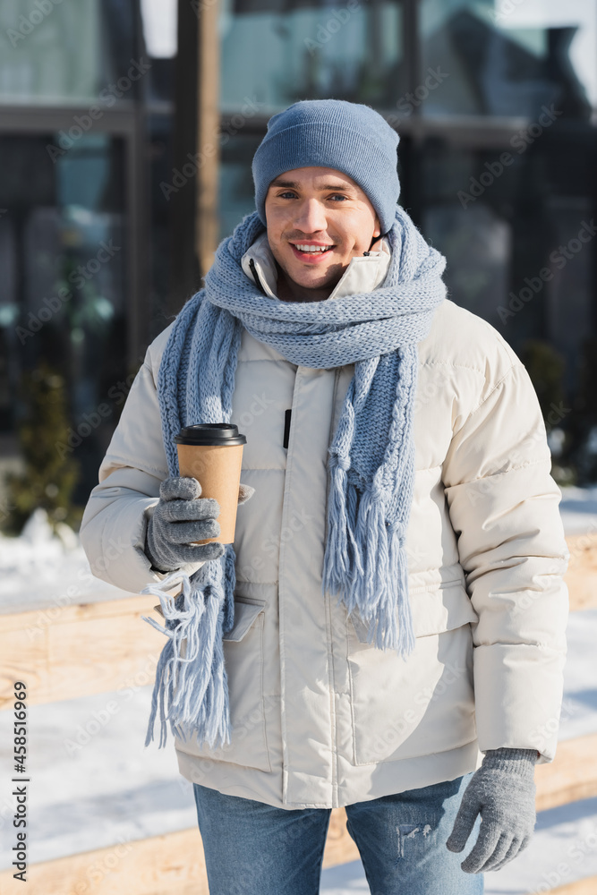happy young man in winter hat and scarf holding paper cup outside happy young man in winter hat and scarf holding paper cup outside