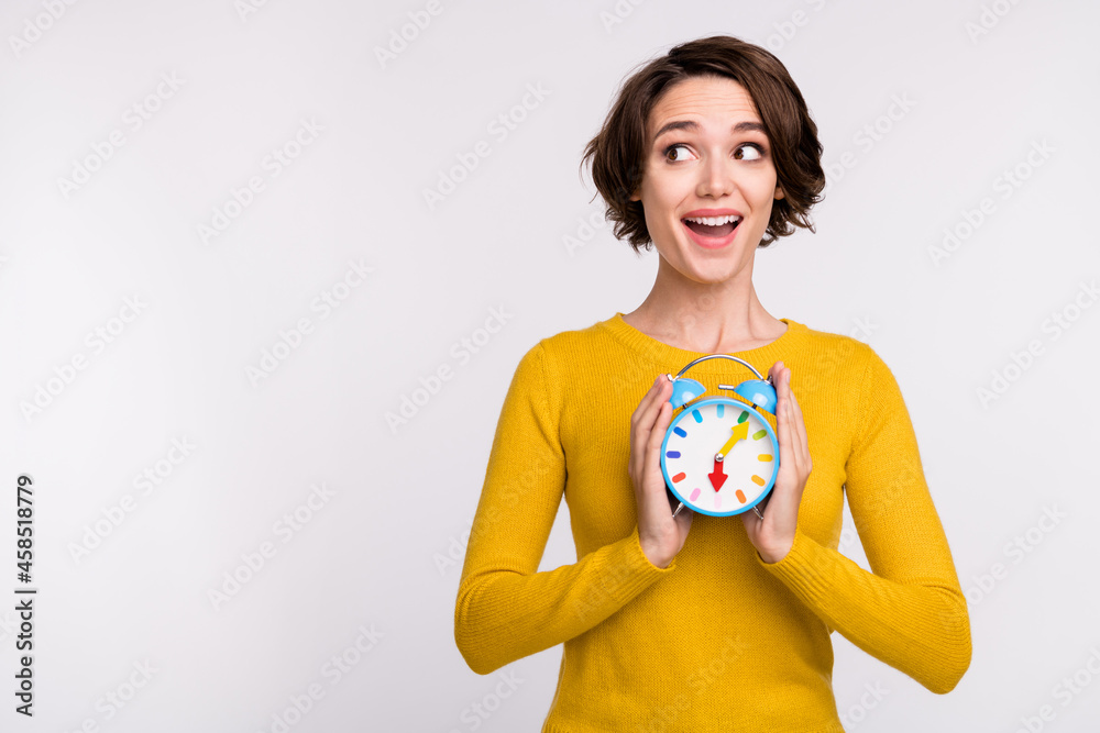 Photo of impressed brunette millennial lady hold clock look empty space wear yellow shirt isolated on grey color background