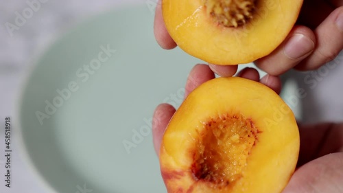 The process of both slicing the peach and dividing it into two halves. Juicy and ripe fresh fruits