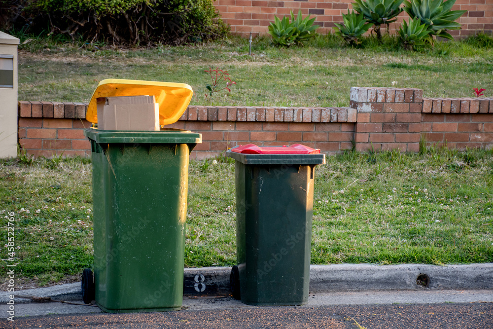 Australian garbage wheelie bins with colourful lids for general and recycling household waste on the street kerbside for council rubbish collection. Australian garbage wheelie bins with colourful lids for general and recycling household waste on the street kerbside for council rubbish collection.