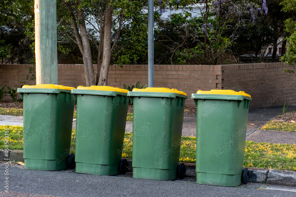 Australian garbage wheelie bins with colourful lids for recycling household waste on the street kerbside for council rubbish collection. Australian garbage wheelie bins with colourful lids for recycling household waste on the street kerbside for council rubbish collection.