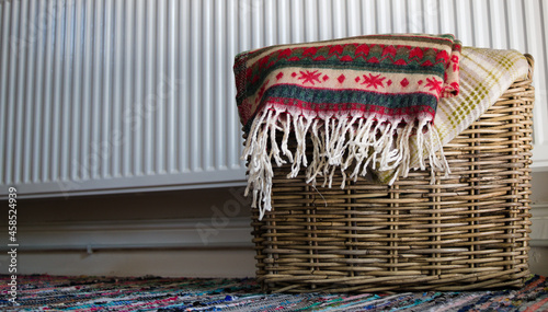 Warm blankets in wicker basket in front of the radiator