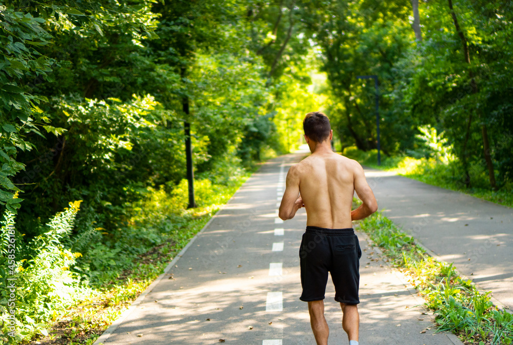 Morning jogging, running in the city park. Athletic man running down the track.