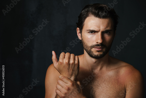 Young half-naked man holding his wrist and looking at camera © Drobot Dean