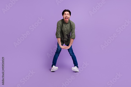 Full size photo of funny funky happy young man hold hands together good mood enjoy isolated on purple color background