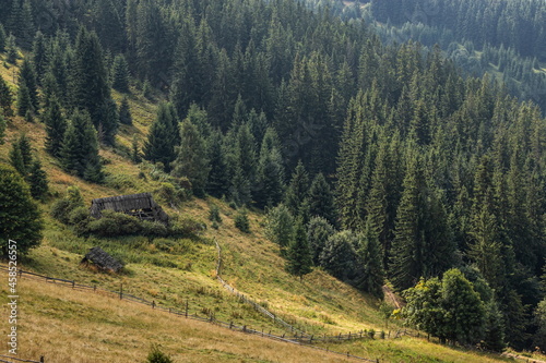 Abandoned buildings in the mountains, wooden houses against the background of rocks, the natural landscape, green meadows and forests